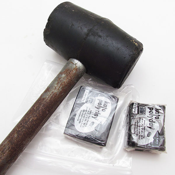Two blocks of black Kato polymer clay with a mallet